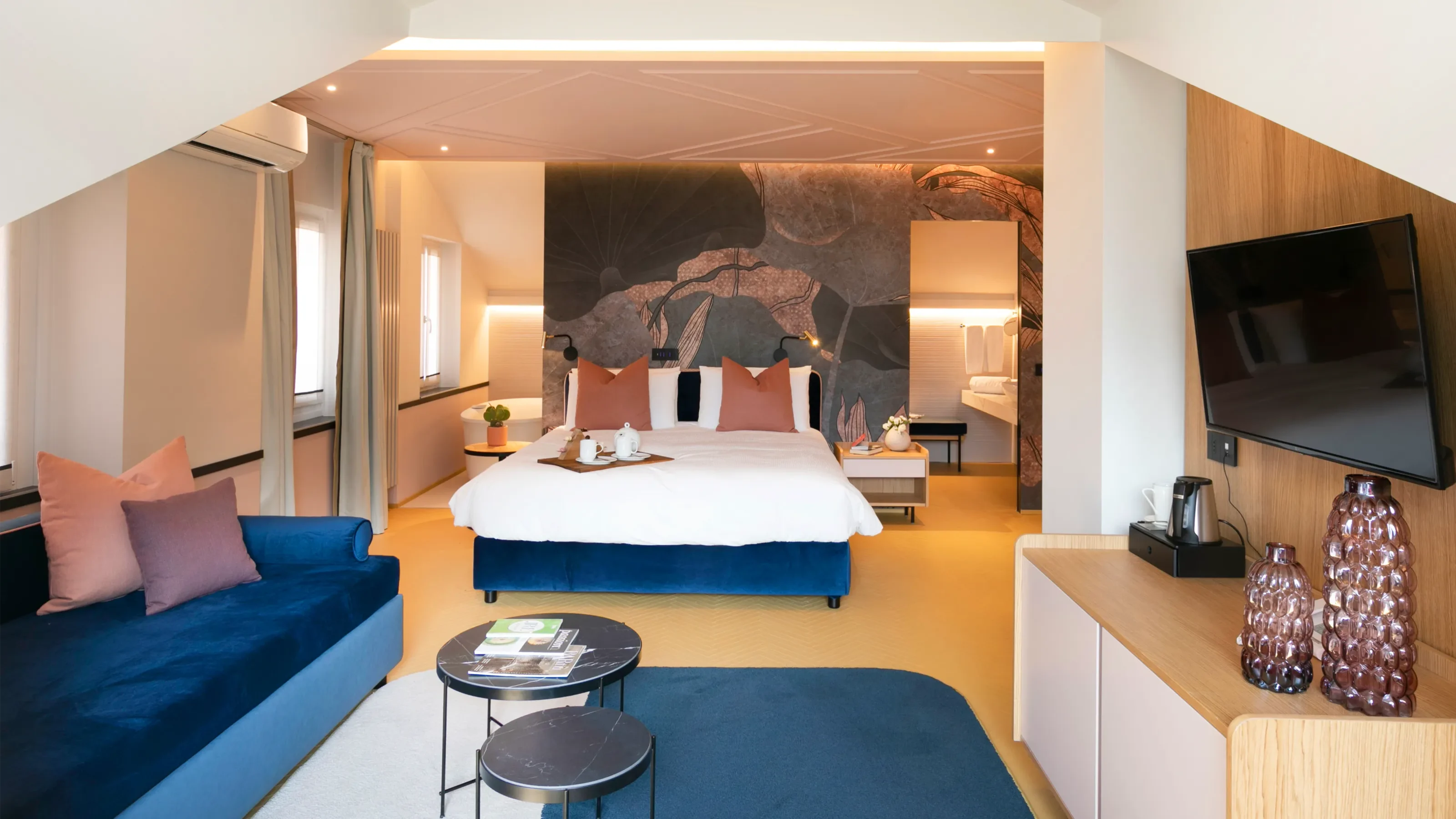 Junior Suite Eurossola con salottino, letto e bagno sullo sfondo
